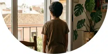 Niño de espaldas mirando por la ventana en casa en Sevilla